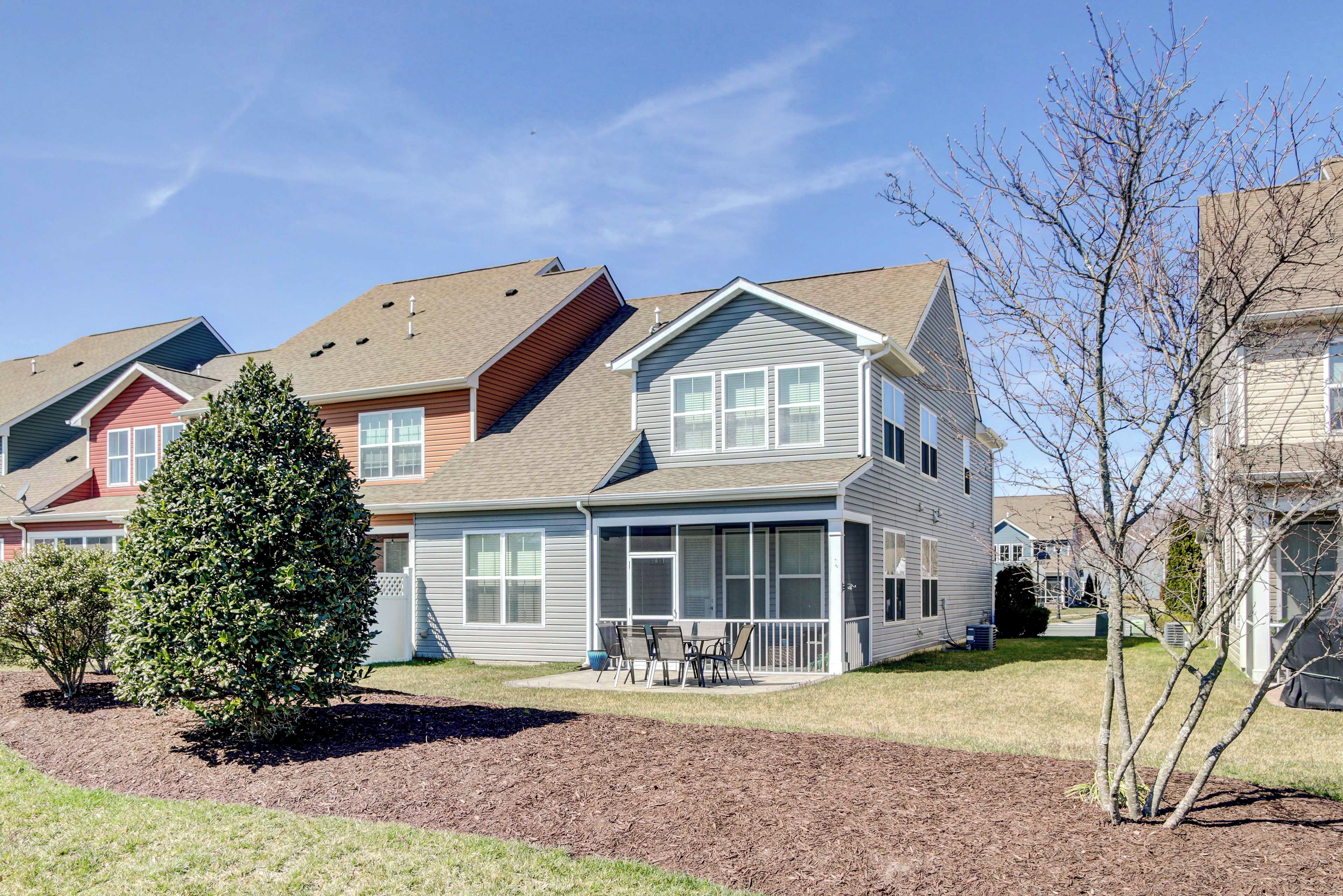 A residential building with a covered patio, a well-maintained lawn, and a large evergreen tree.