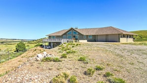 A modern house with a large deck, a covered patio, and a view of the surrounding landscape. - Sunny Big Timber Retreat w/ Spacious Deck! (Big Timber)