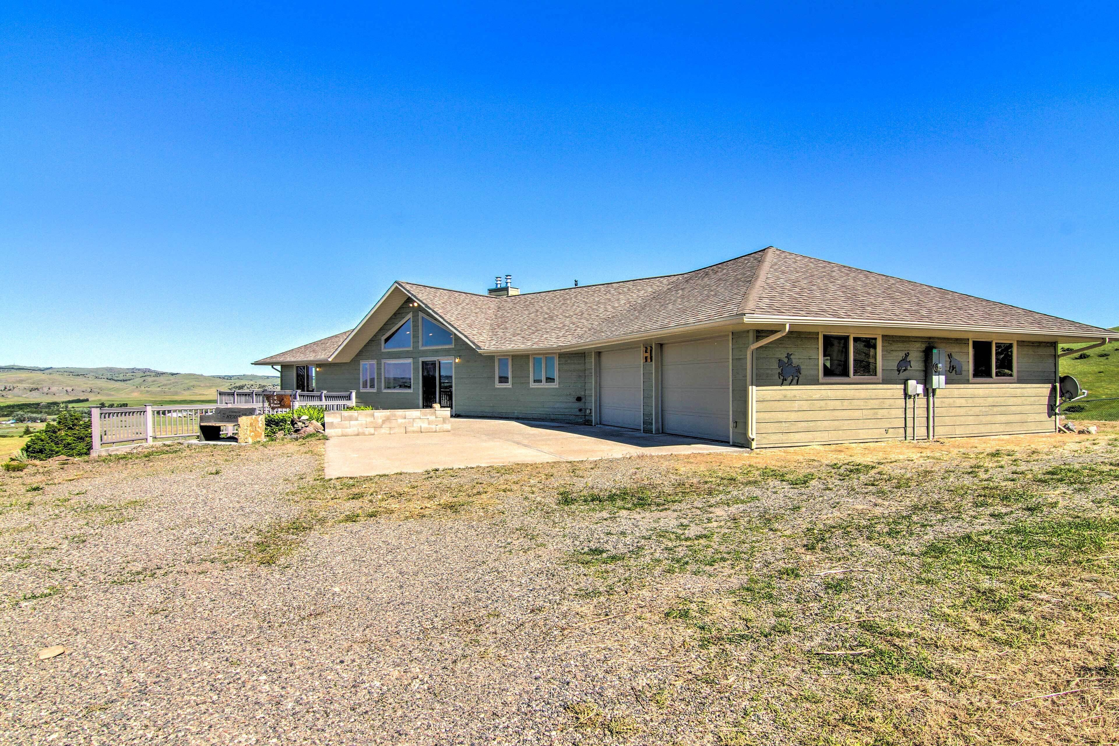A two-story building with a sloped roof, a covered porch, and a gravel driveway.