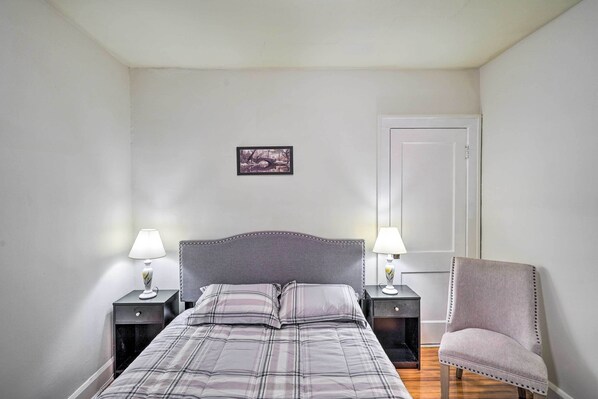 A neatly arranged bedroom with a bed, two bedside tables with lamps, a chair, and a door.