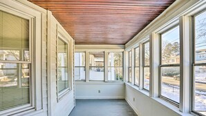 Un couloir étroit, avec de grandes fenêtres de chaque côté, un plafond en bois et une vue sur une rue résidentielle.