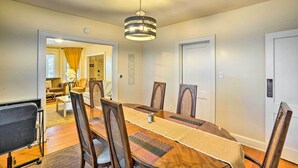 Un espace repas comprenant une longue table en bois, six chaises et un luminaire suspendu.