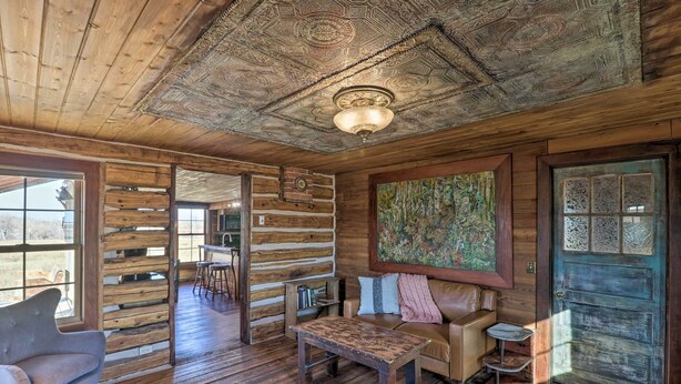 A rustic interior with wooden walls, a sofa, a coffee table, and a dining area. - Rustic & Rural Cabin in Dupuyer on Open 14 Acres! (Dupuyer)