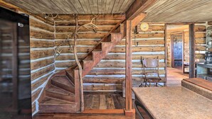 A log cabin interior with a wooden staircase, rustic decor, and a kitchen area. - Rustic & Rural Cabin in Dupuyer on Open 14 Acres! (Dupuyer)