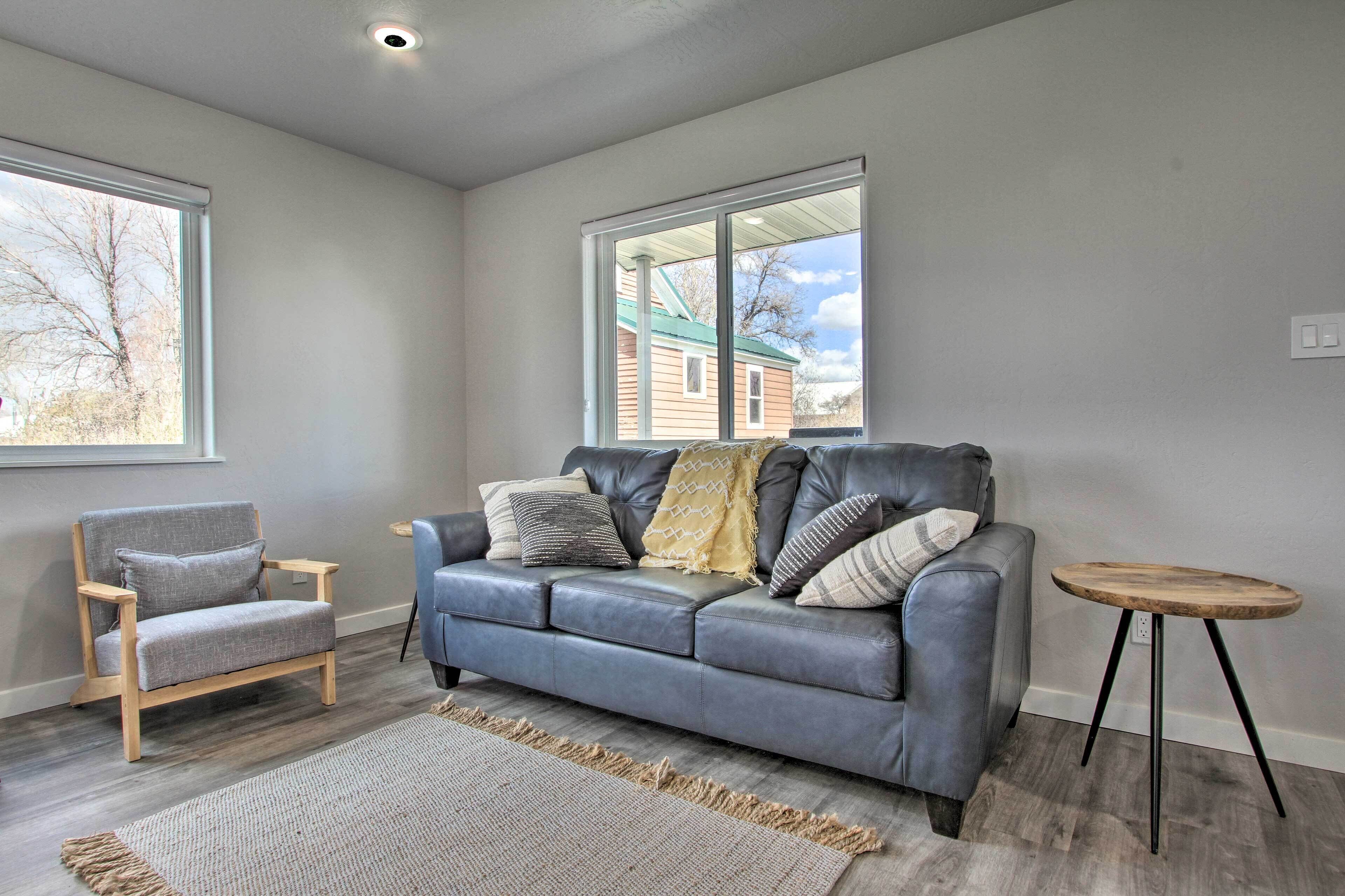 A living room with a grey sofa, a wooden chair, and a small round table.