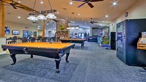 A pool table area with ceiling fans, a brick wall, and a vending machine.