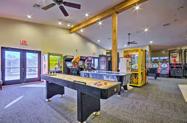 A room with a foosball table, arcade games, and an exit sign.