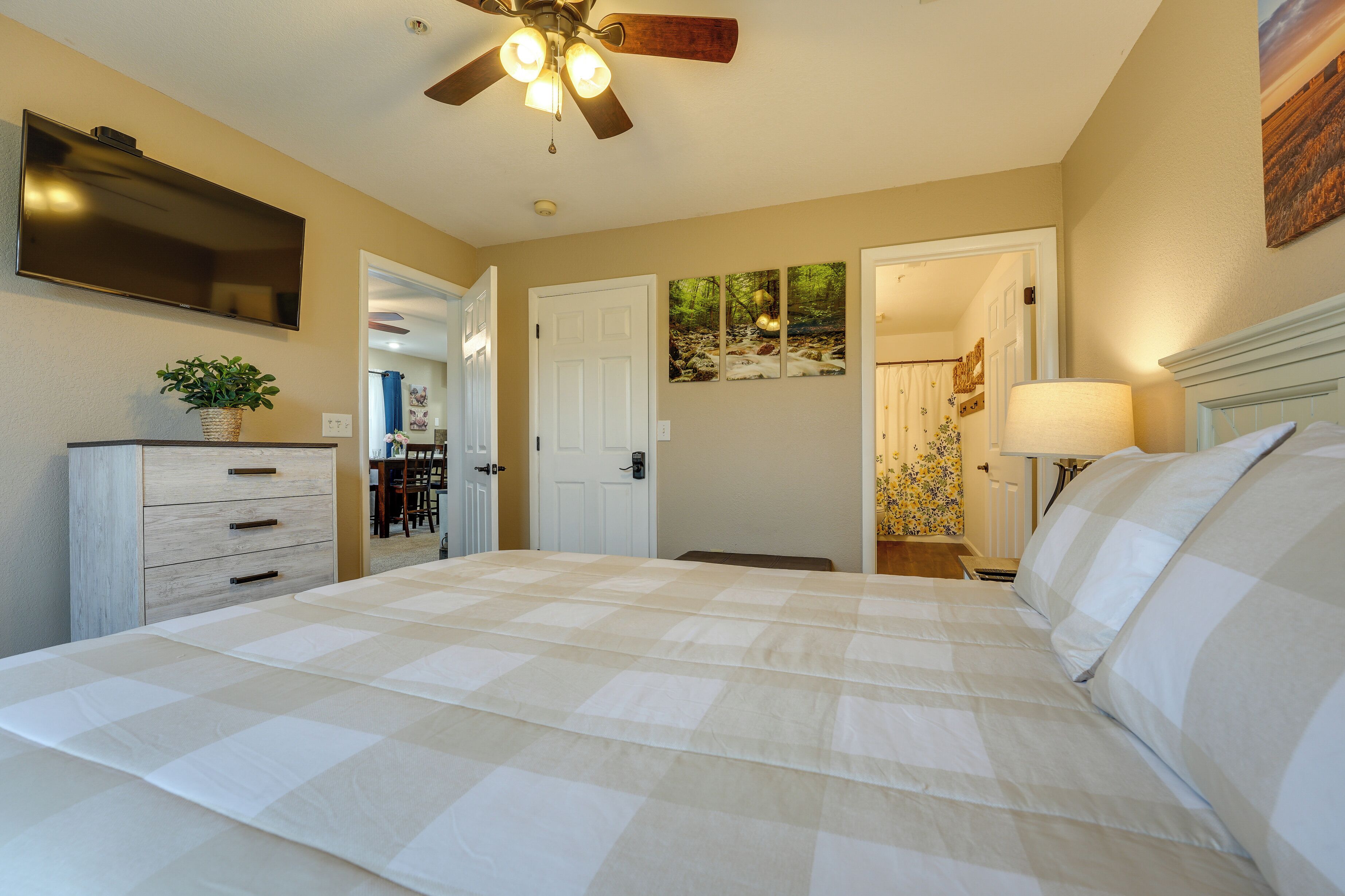 A bedroom with a bed, a ceiling fan, a TV, and a dresser.