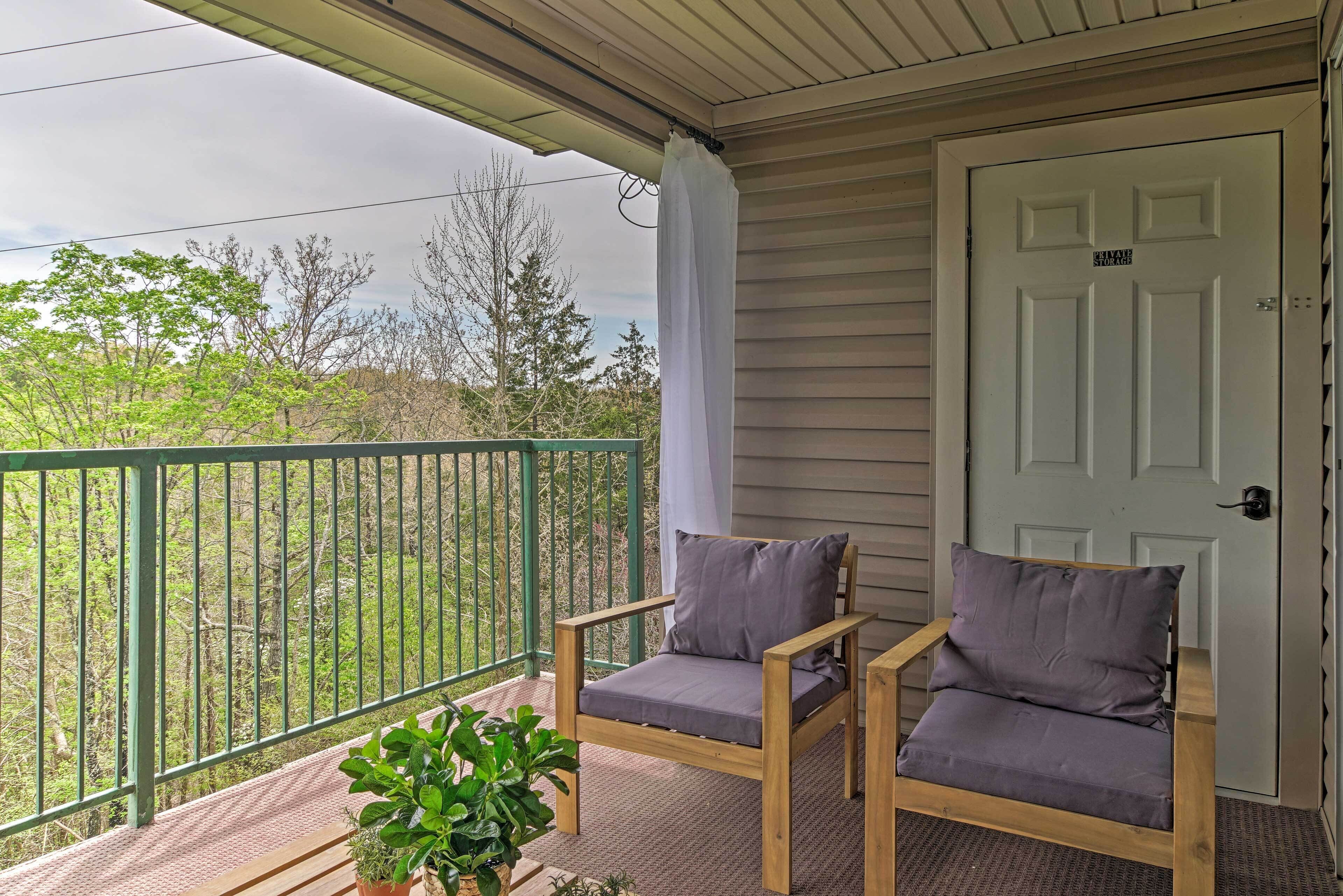 A wooden porch with a green railing, two cushioned chairs, and a door labeled "STAY SAFE."