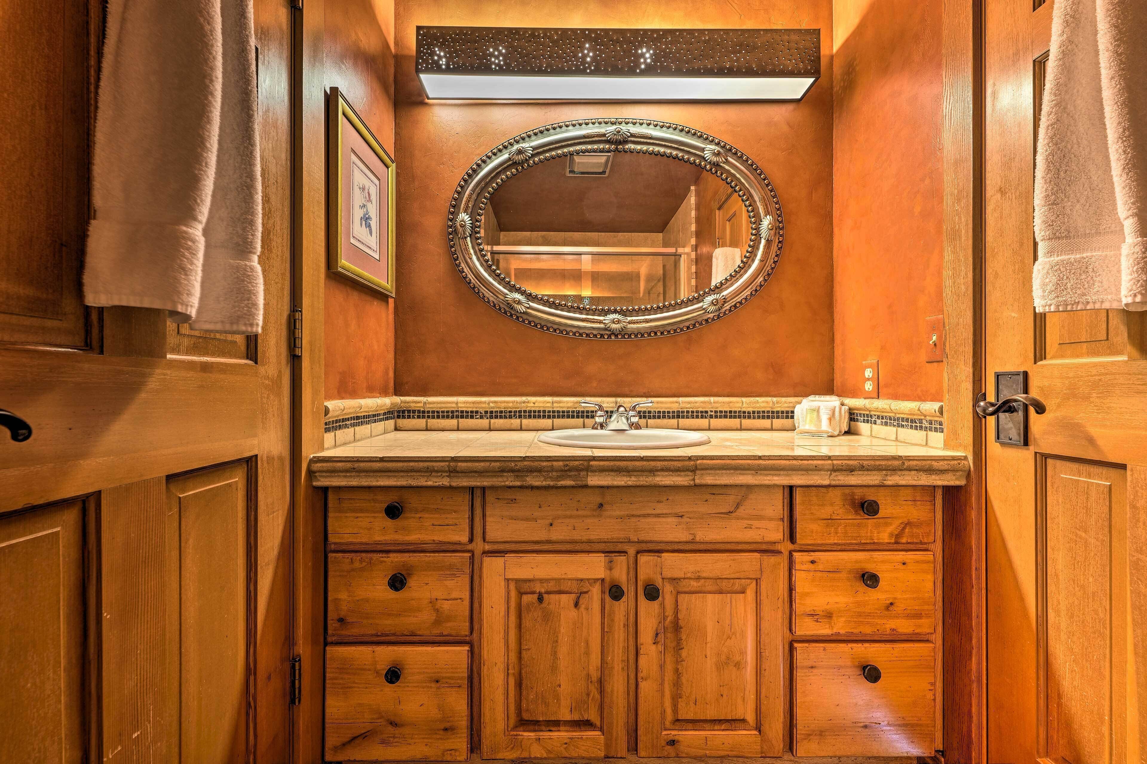 A wooden bathroom with a large mirror, a sink, and multiple drawers.