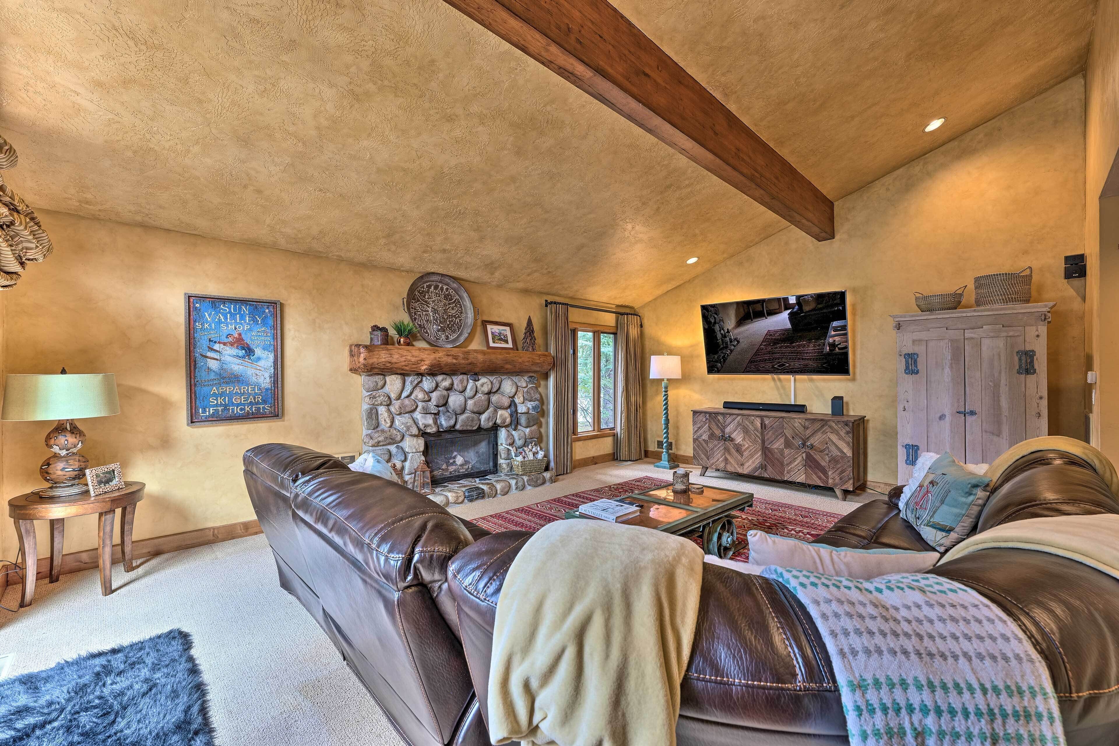 A cozy living room with a stone fireplace, leather furniture, and a television.