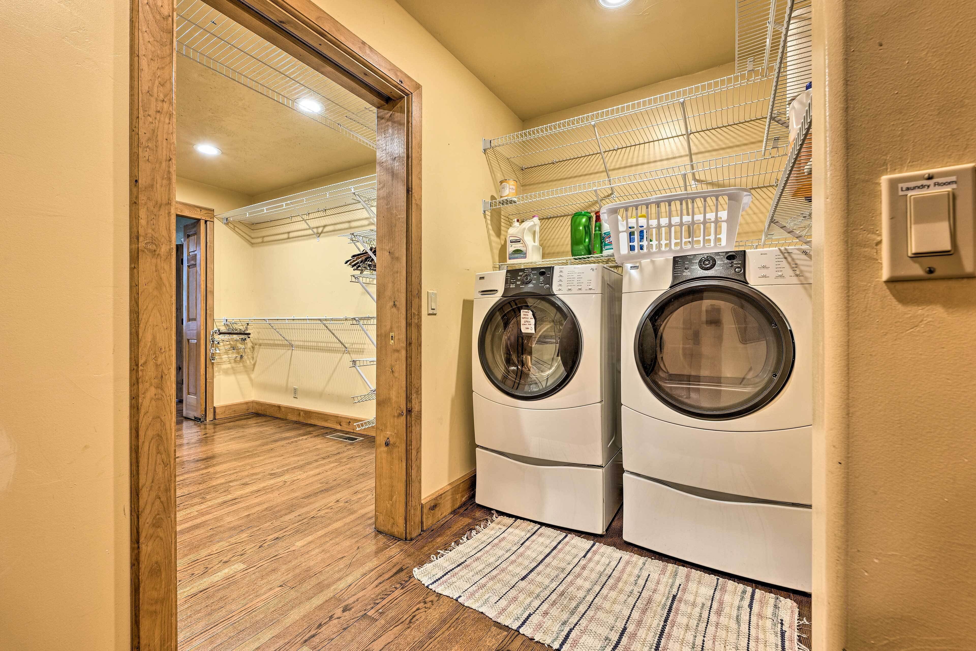 A laundry room with two front-loading washing machines, a drying rack, and a wooden floor.