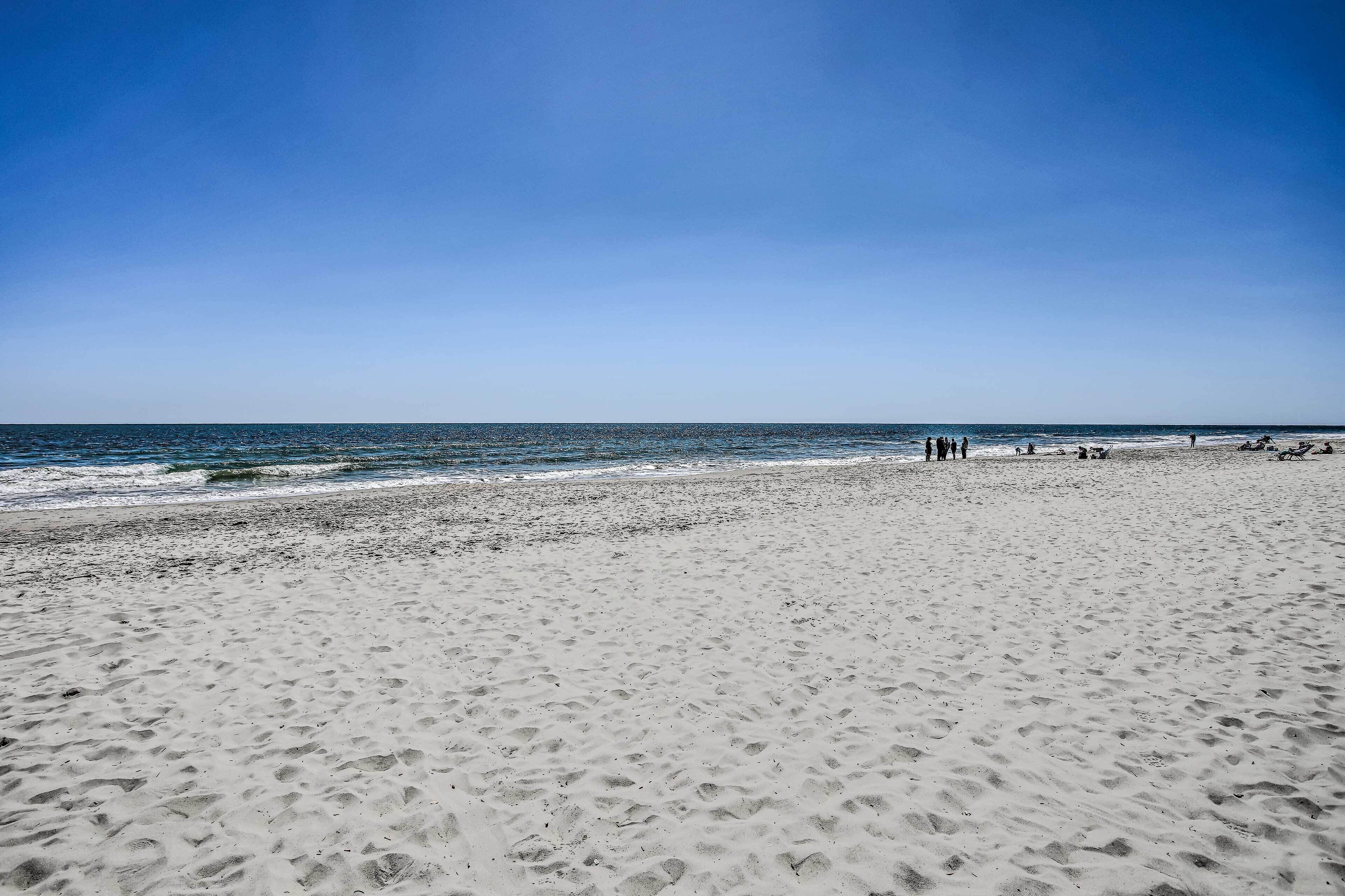 Une vaste plage de sable fin, avec l’océan en toile de fond.