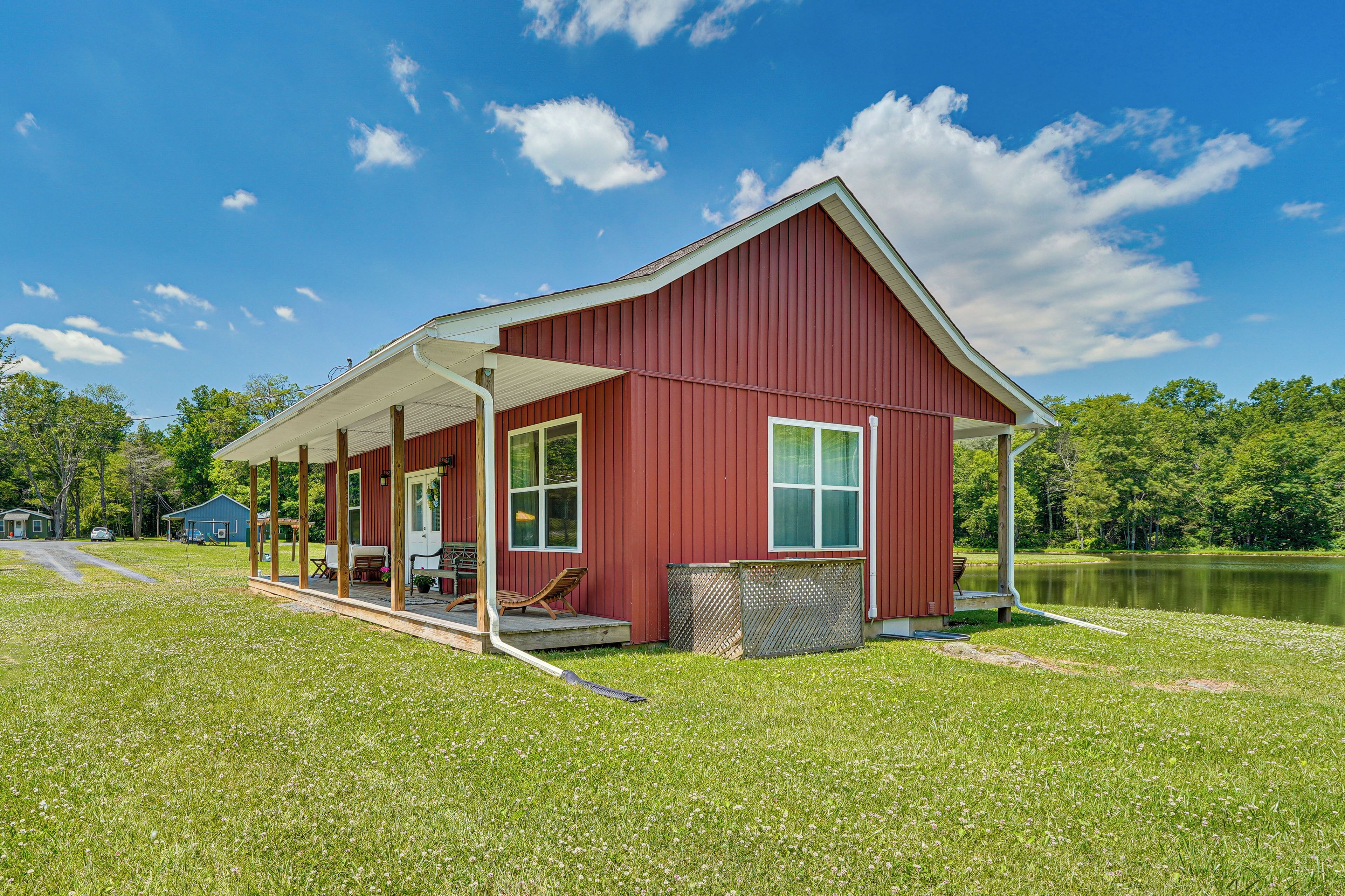 A red building with a porch, a small deck, and a view of a lake.