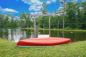 A red floating platform with a wooden pergola structure, surrounded by a grassy area and a body of water. - Close to Slopes: Lakeside Cottage in Pocono Mtns (Brodheadsville)