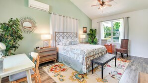 Un dormitorio con cama, escritorio, silla y un ventanal grande.