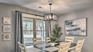 A dining room with a dark wooden table, white chairs, and a hanging light fixture.