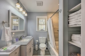 A modern bathroom with a sink, mirror, toilet, and shower.