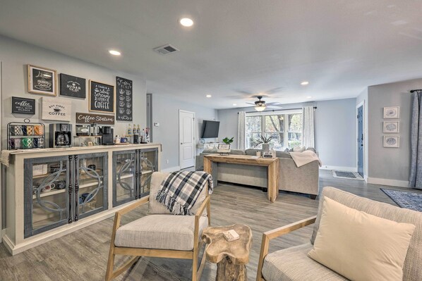 A modern living room with a coffee station, a sofa, and a wooden coffee table.