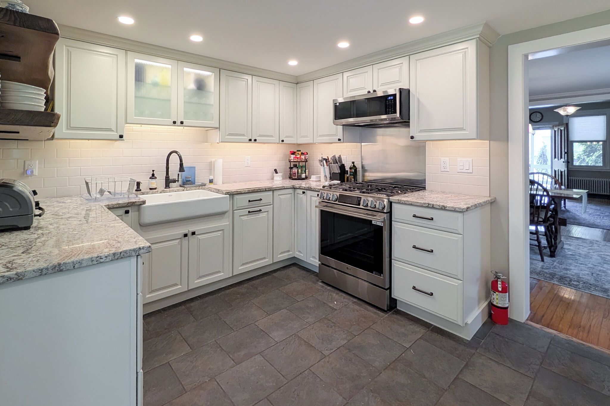 A modern kitchen with white cabinets, a stainless steel stove, and a microwave.