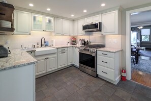 A modern kitchen with white cabinets, a stainless steel stove, and a microwave. - Charming Abode w/ Patio - Walk to Town + River! (Stockton)