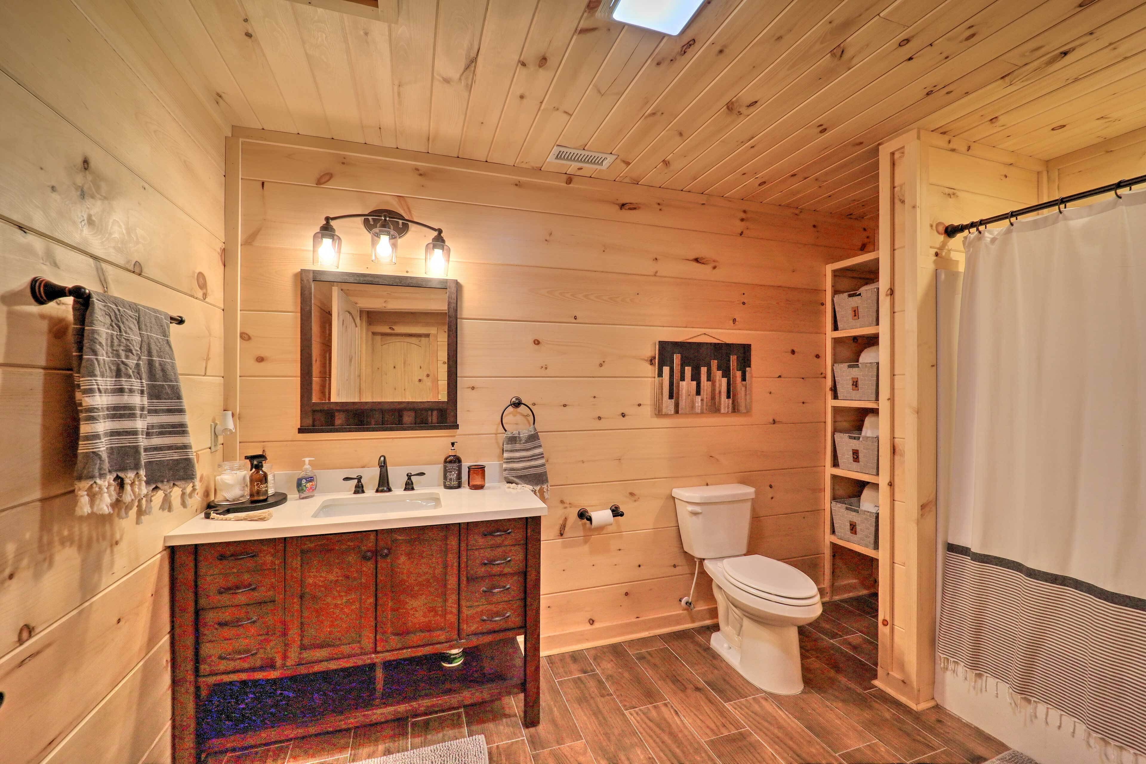 A wooden cabin bathroom with a wooden vanity, a toilet, and a shower curtain.