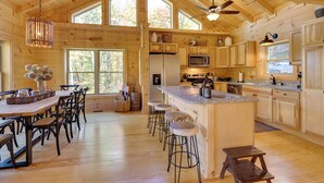Une cuisine spacieuse avec des meubles en bois, un grand îlot central doté de tabourets et un ventilateur de plafond.