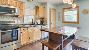 A modern kitchen with wooden cabinets, stainless steel appliances, a large island, and pendant lighting. - Waterfront, Deck: Peaceful Louisa Cottage Escape (Louisa)