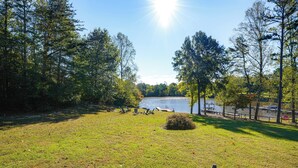 A grassy area with a lake, trees, and a boat dock. - Waterfront, Deck: Peaceful Louisa Cottage Escape (Louisa)