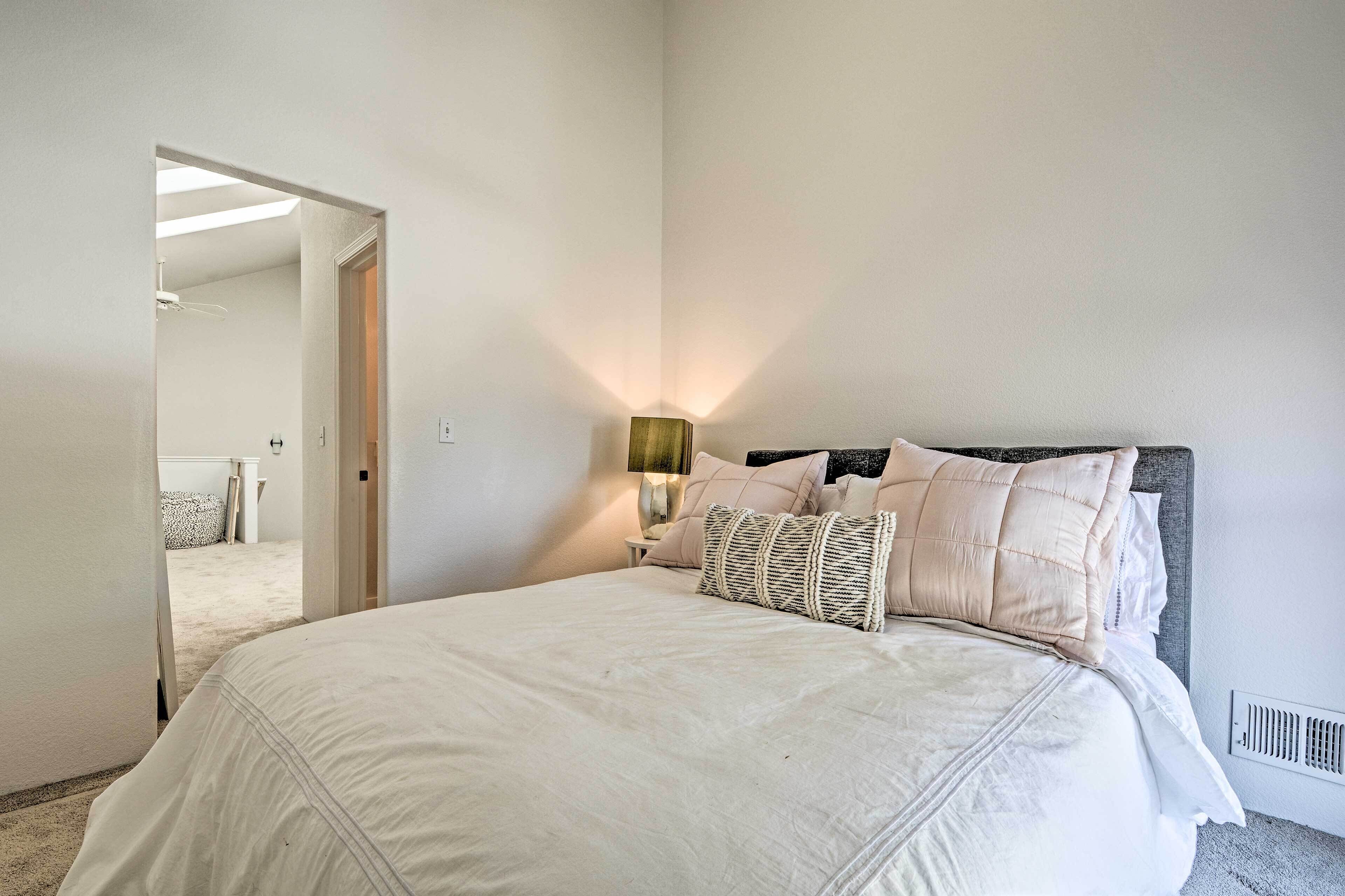 Una camera da letto con un letto grande, una lampada sul comodino e una porta che dà su un'altra stanza.