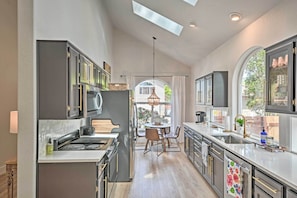 Una cocina moderna con una isla central, armarios oscuros y un ventanal que proporciona luz natural.