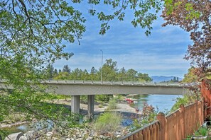 Un pont en béton enjambant une rivière, avec une clôture en bois et de la végétation au premier plan.