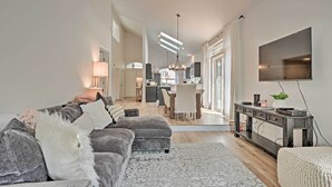 Ein modernes Wohnzimmer mit einem grauen Sofa, einem gemusterten Teppich und einem Fernseher an der Wand.