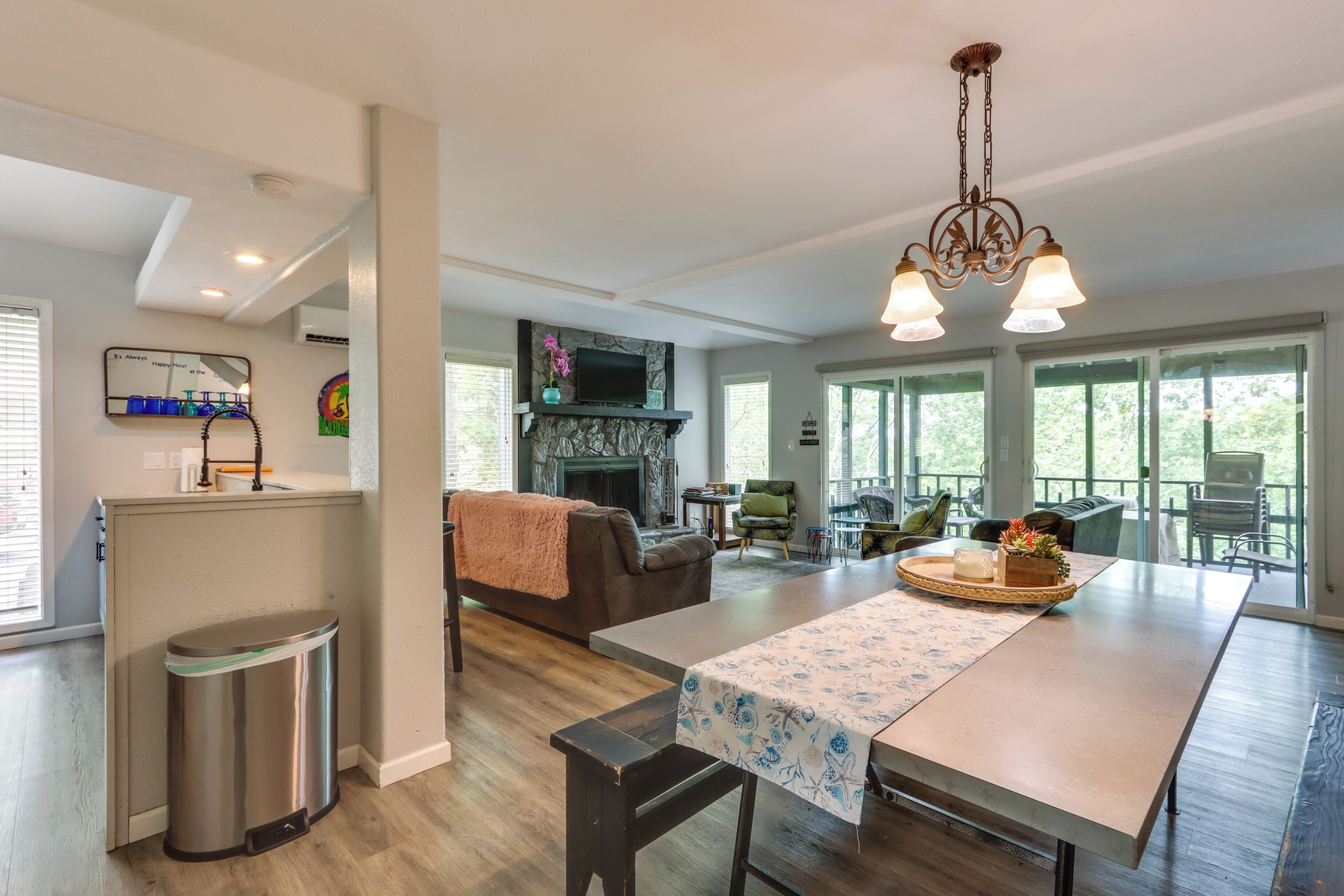 A spacious living area with a fireplace, a dining table, and a large window providing natural light.