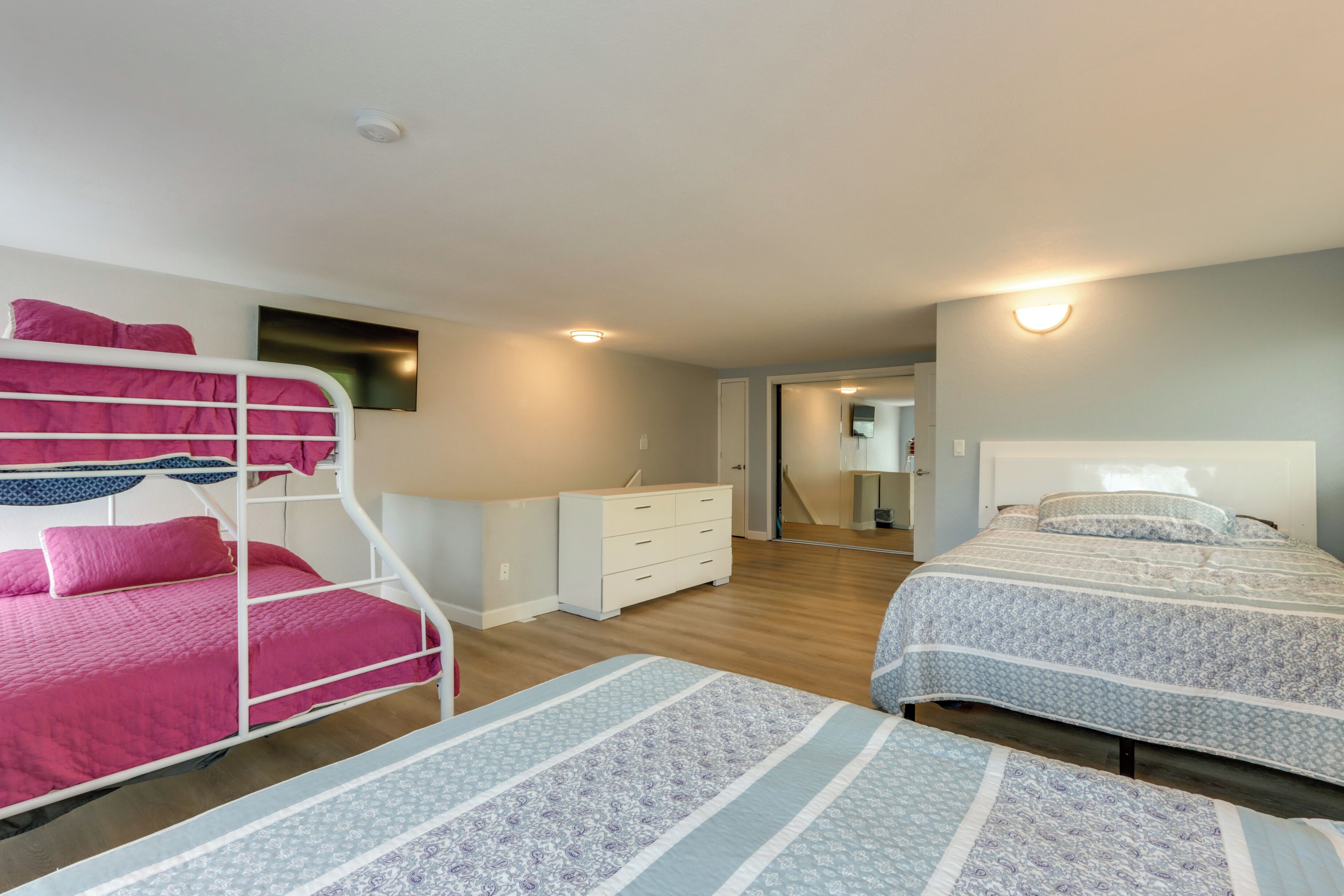 A bedroom with bunk beds, a single bed, a dresser, and a TV.