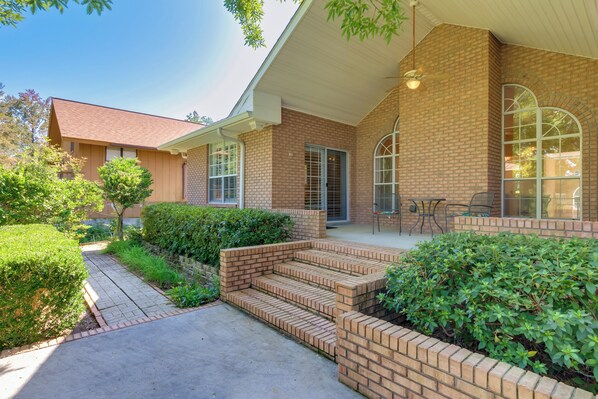 A brick house with a covered porch, a small garden, and a clear sky. - Chic Home w/ Club Access Near Bay St Louis! (Diamondhead)