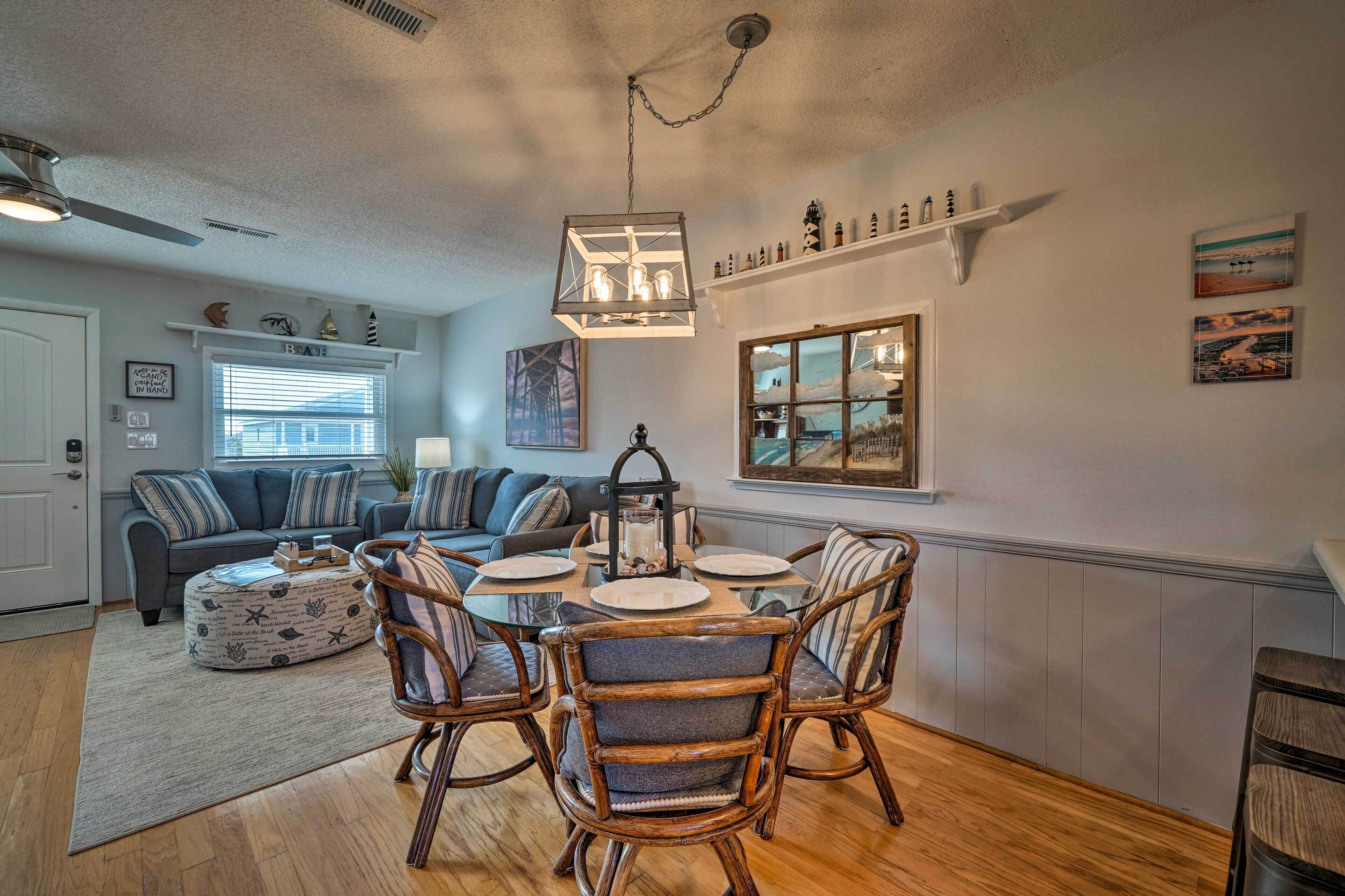 A dining area with a round table, four chairs, and a hanging light fixture.
