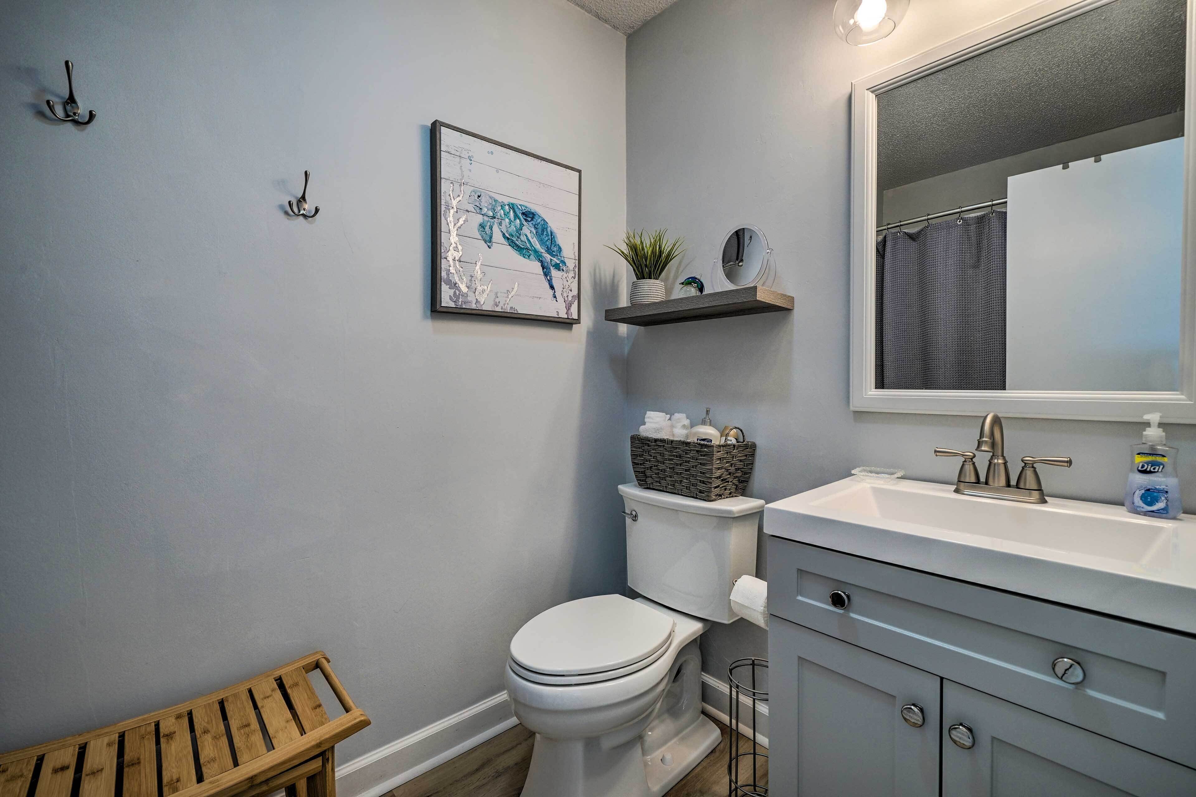 Une salle de bain équipée de toilettes, d’un lavabo, d’un miroir et d’un tableau encadré accroché au mur.