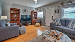 A living room with a grey sofa, a wooden entertainment unit, a television, and a ceiling fan.
