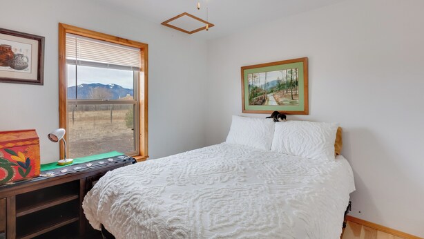A bedroom with a bed, a desk, a chair, a ceiling fan, a window with blinds, and a framed picture on the wall. - Ideally Located Taos Vacation Rental w/ Gas Grill (Ranchos De Taos)