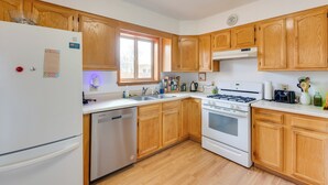 A kitchen with wooden cabinets, a white refrigerator, a dishwasher, a stove, and a window. - Ideally Located Taos Vacation Rental w/ Gas Grill (Ranchos De Taos)