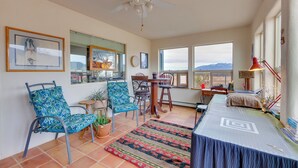 A spacious room with a ceiling fan, large windows, a dining table, chairs, and a bed. - Ideally Located Taos Vacation Rental w/ Gas Grill (Ranchos De Taos)