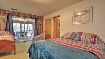 A bedroom with a large bed, a smaller bed, a dining table, and a door leading to a balcony.
