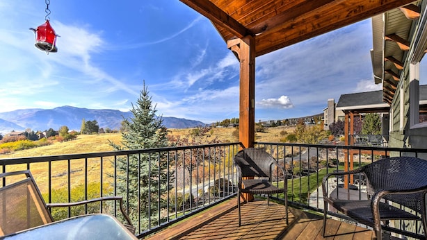 A wooden deck with outdoor furniture, a hanging bird feeder, and a view of mountains and a grassy field. - Eden Townhome w/ Mtn View + Shuttle to Powder Mtn! (Eden)