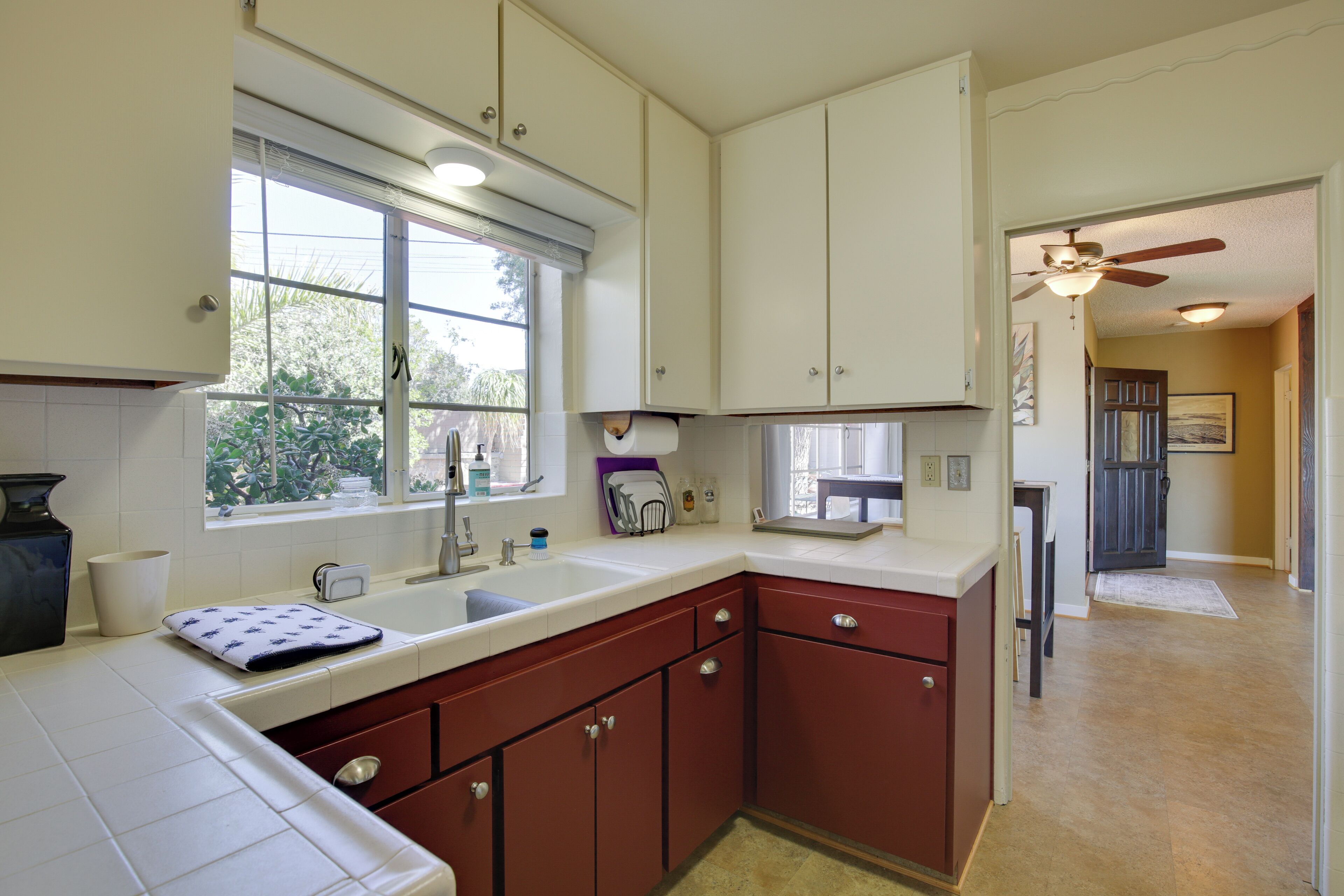 A kitchen with white cabinets, a window, and a ceiling fan.