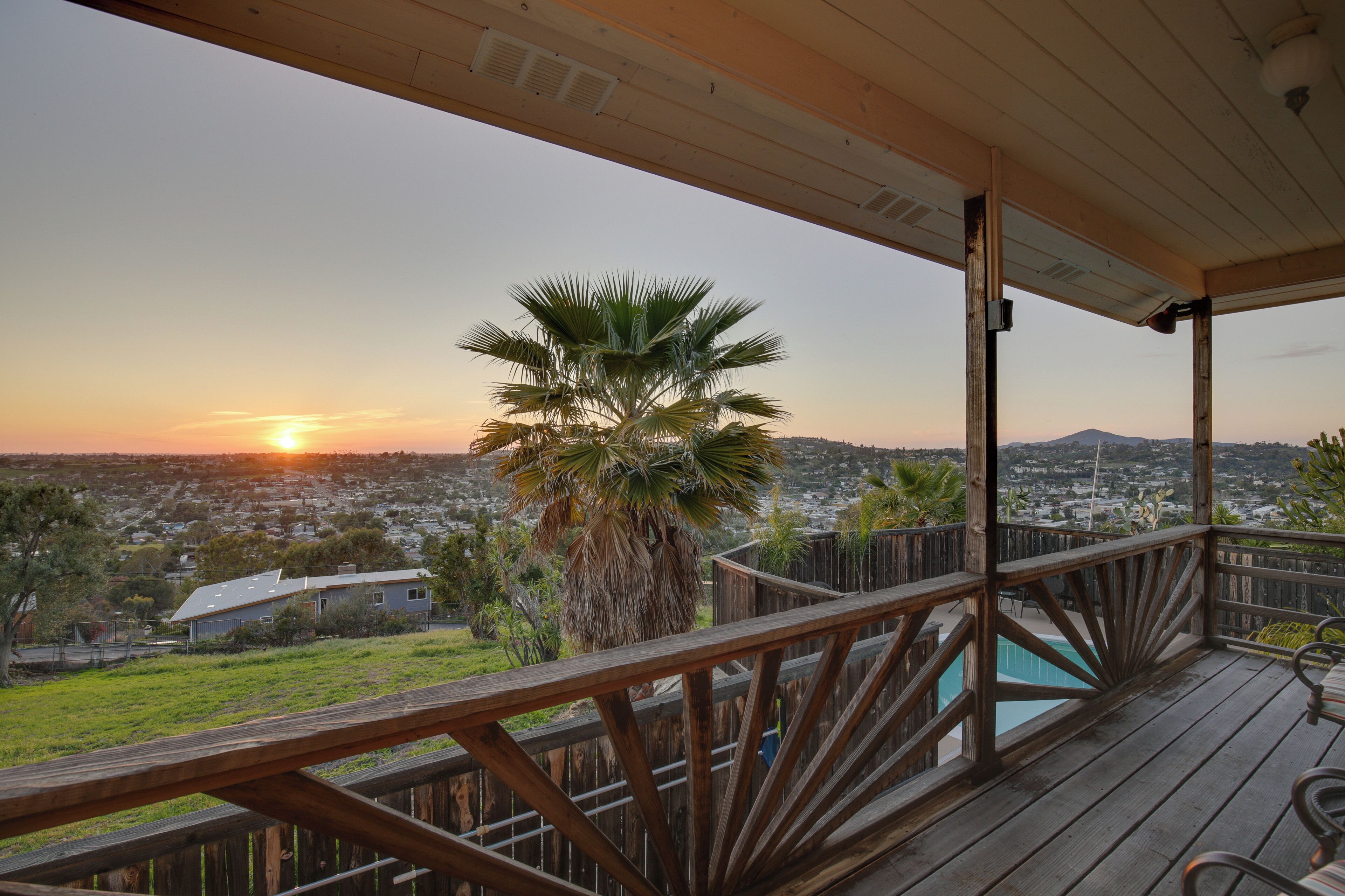 A wooden deck with a view of a residential area and a mountain in the distance.