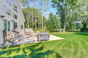A backyard with a covered grill, outdoor furniture, and a wooden deck leading to a house. - Whitehall Retreat w/ Hot Tub Near Muskegon Luge (Whitehall)