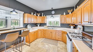 A kitchen with wooden cabinets, a gas stove, and a large window providing natural light.