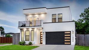 A modern two-story house with a garage, a balcony, and a well-maintained lawn. - Glam Paradaise 5BRs Home in Downtown Dallas (Dallas)