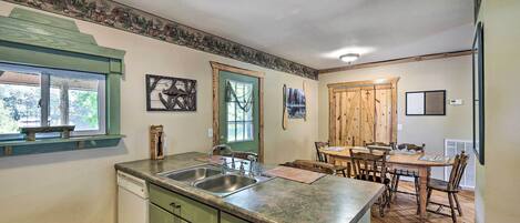 Una cocina con una mesa de comedor de madera, dos fregaderos y una encimera verde.